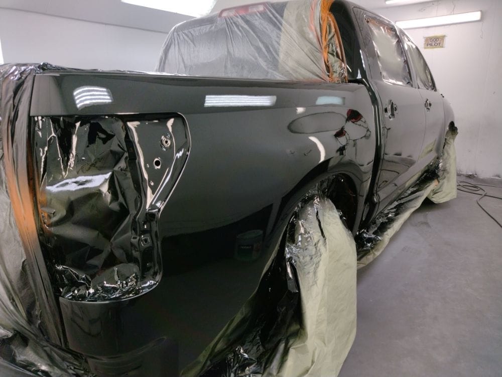 Freshly painted gloss-black truck inside the Auto Shop Repair paint booth